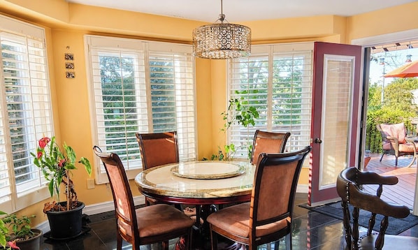 A dining area with a round table, four chairs, and a chandelier.