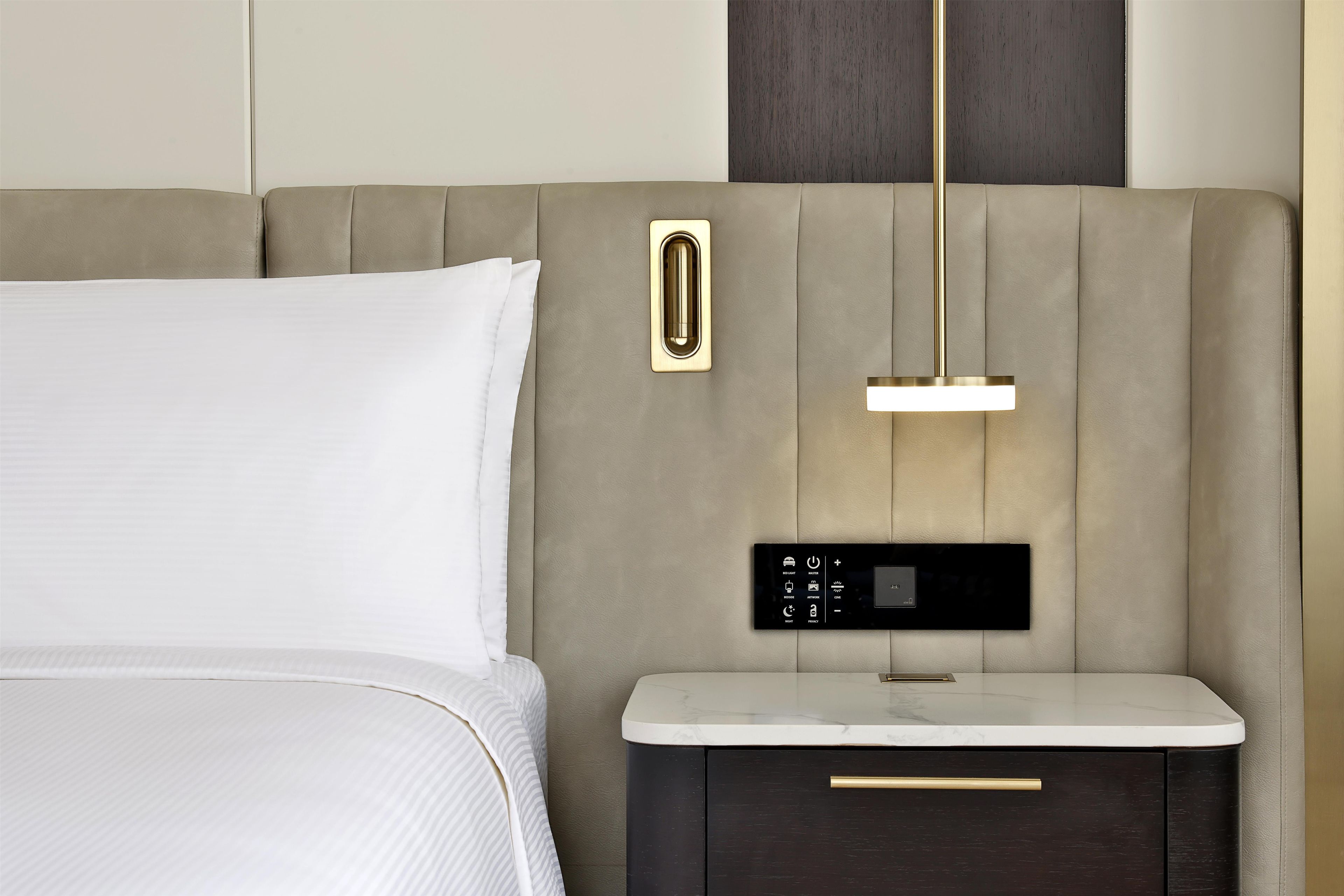 Un letto moderno con testiera, un comodino con cassetto e un pannello di controllo.