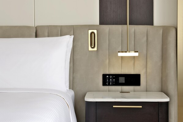 A modern bed with a headboard, a bedside table with a drawer, and a control panel.