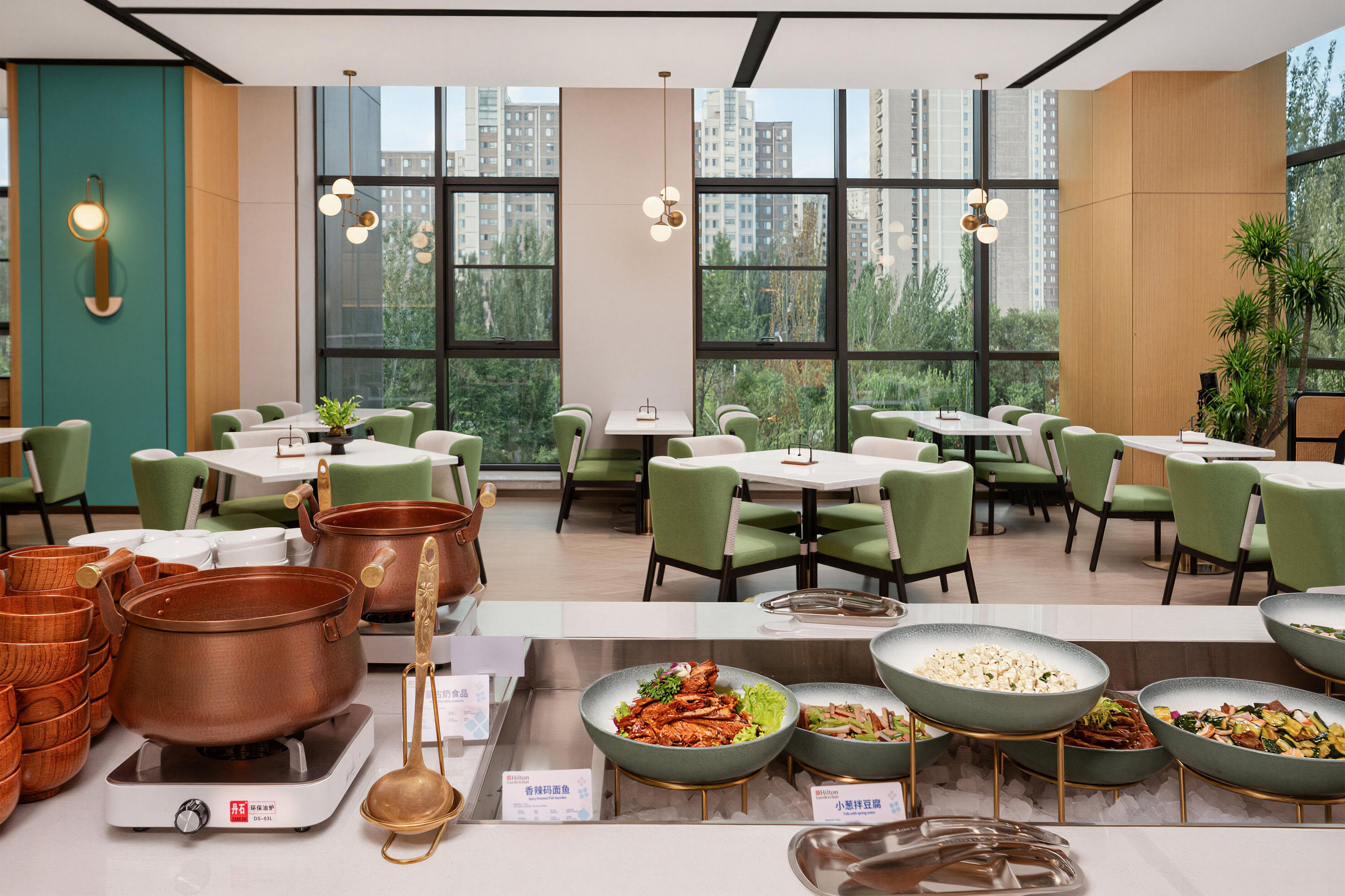 A restaurant with high ceilings, large windows, and a variety of seating arrangements.