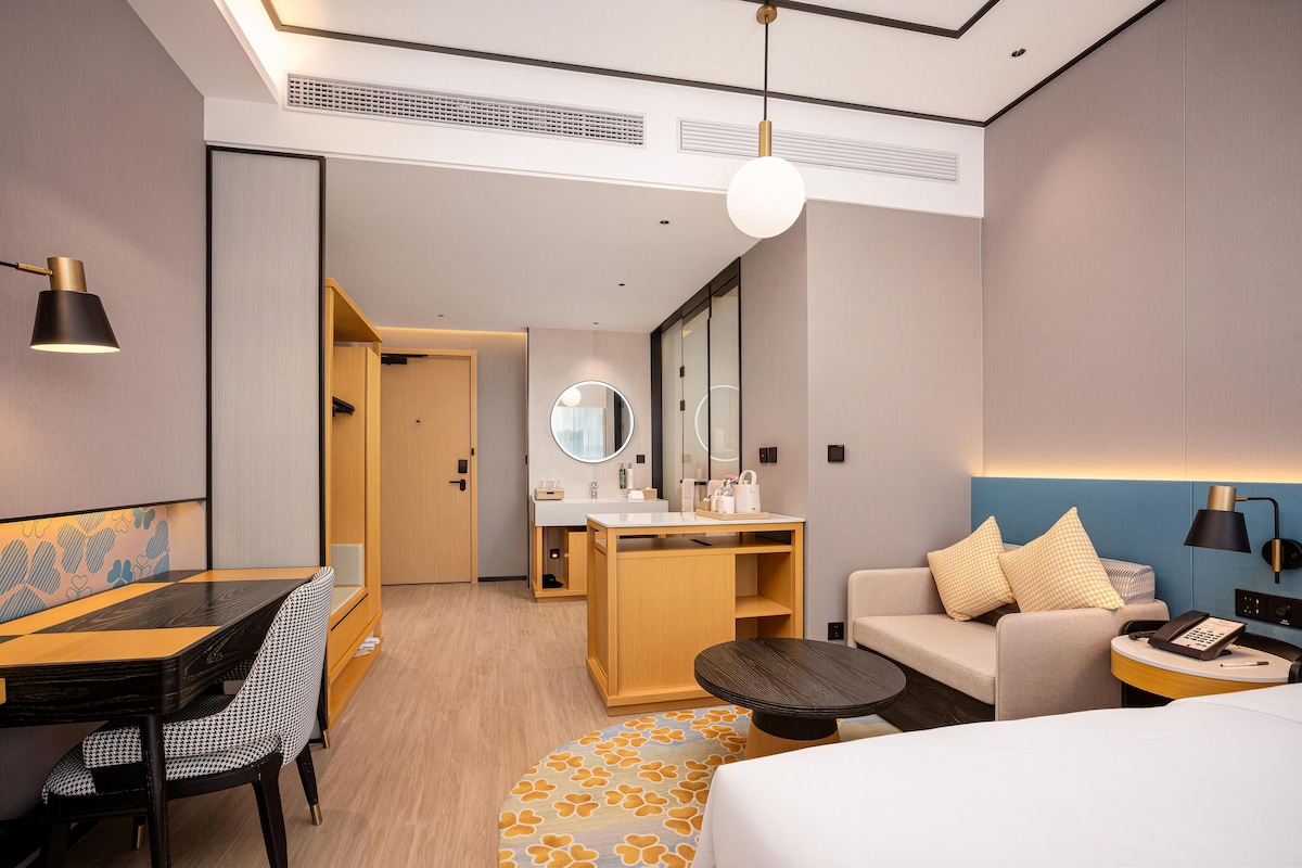 Una habitación de hotel moderna con cama, escritorio, sofá y una mesita.