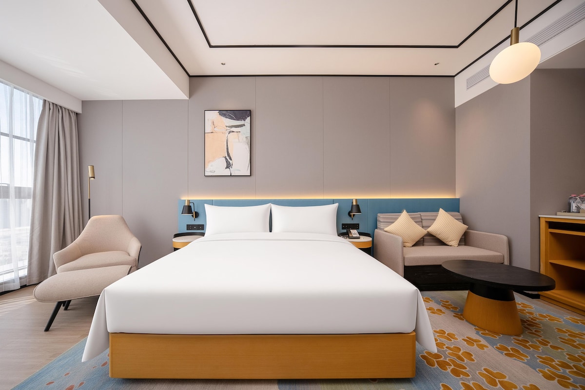 Una habitación de hotel moderna con una cama grande, un sofá, un escritorio y una silla.