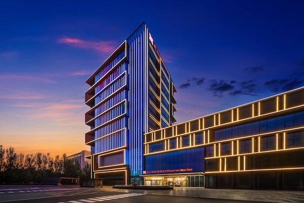 Un moderno edificio de hotel con una entrada destacada y un cielo despejado.