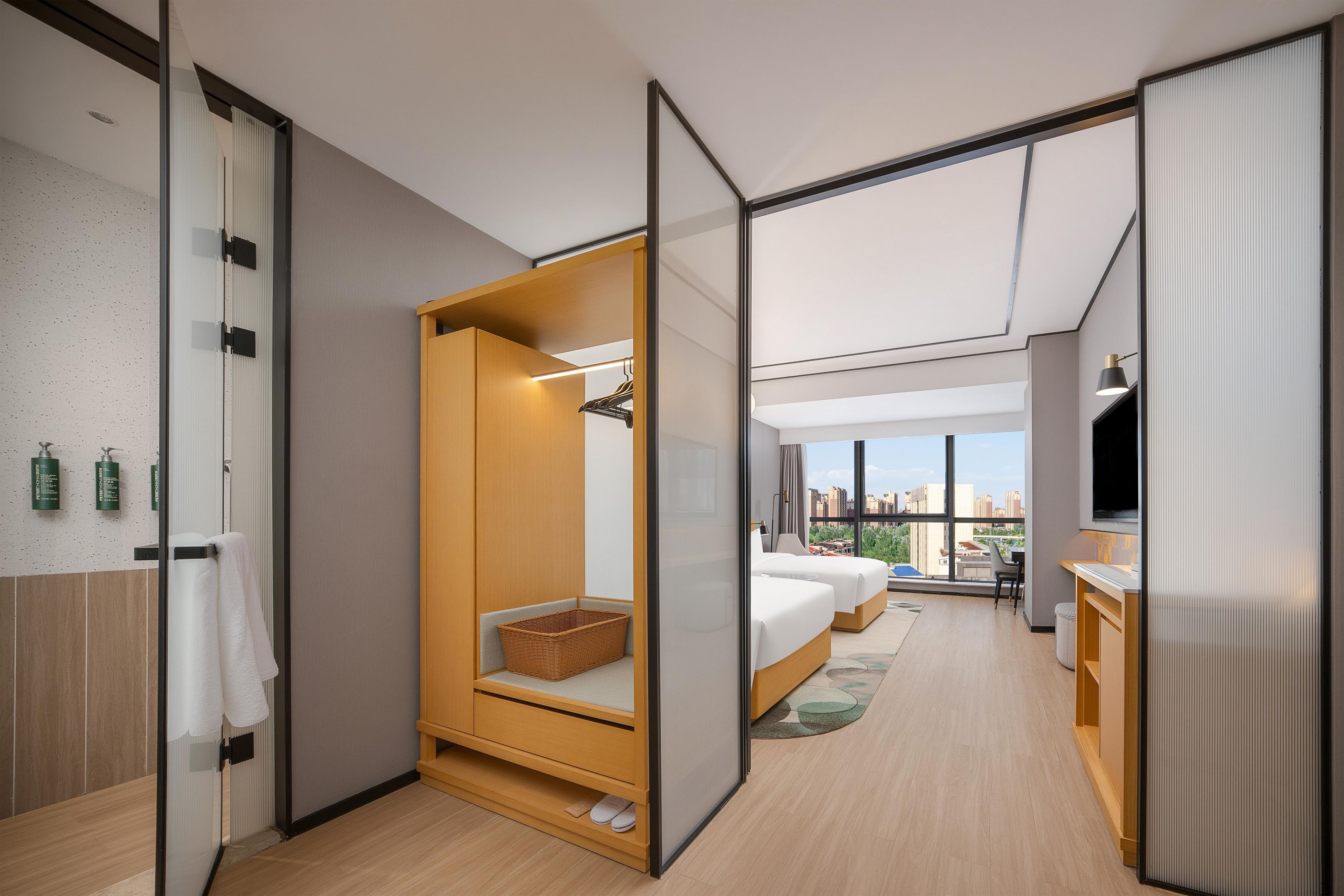 Ein modernes Hotelzimmer mit Schiebetürenschrank, einem Bett mit Blick, einer kleinen Sitzecke und einer Küchenzeile.