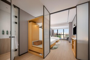 Una habitación de hotel moderna con armario correderas, cama con vistas, una zona de estar pequeña y una kitchenette.