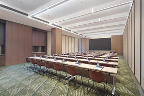 A conference room with multiple tables, chairs, and a projector screen.