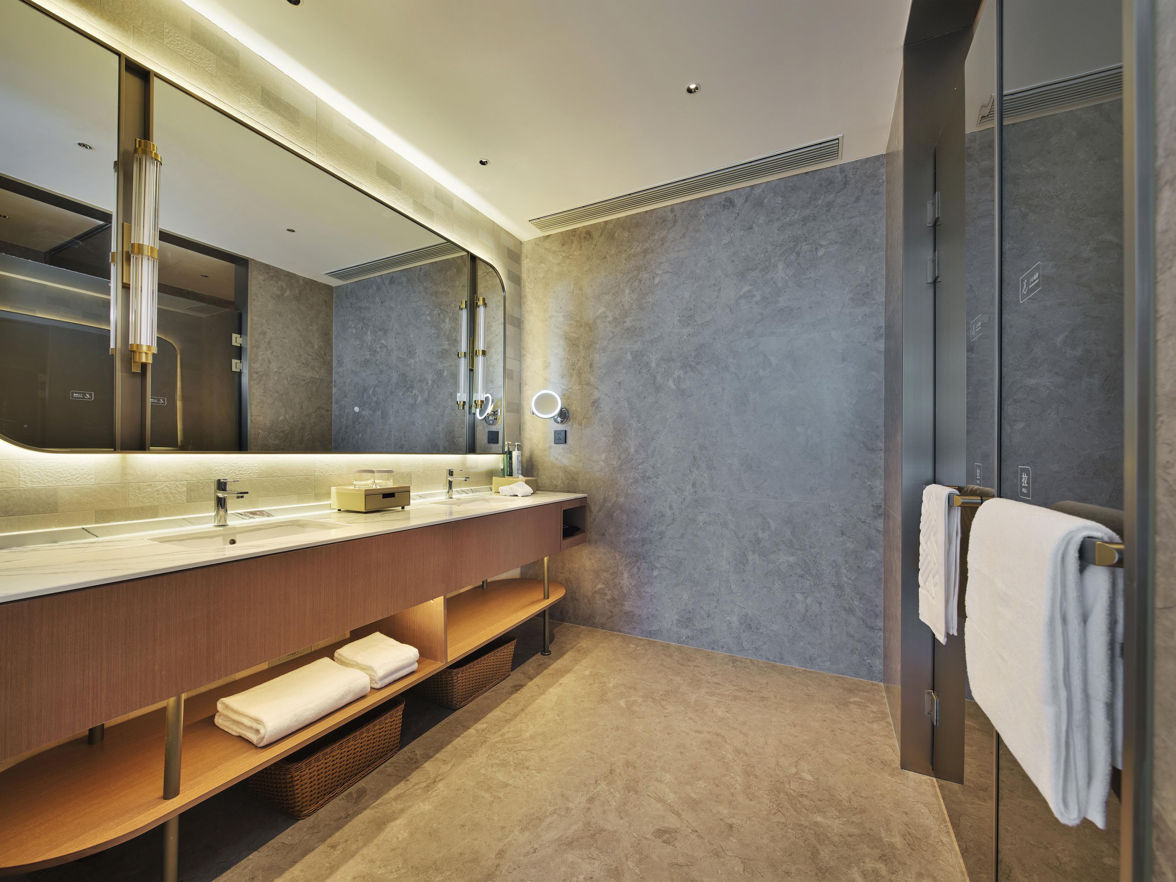A modern bathroom with a large mirror, dual sinks, and a towel rack.