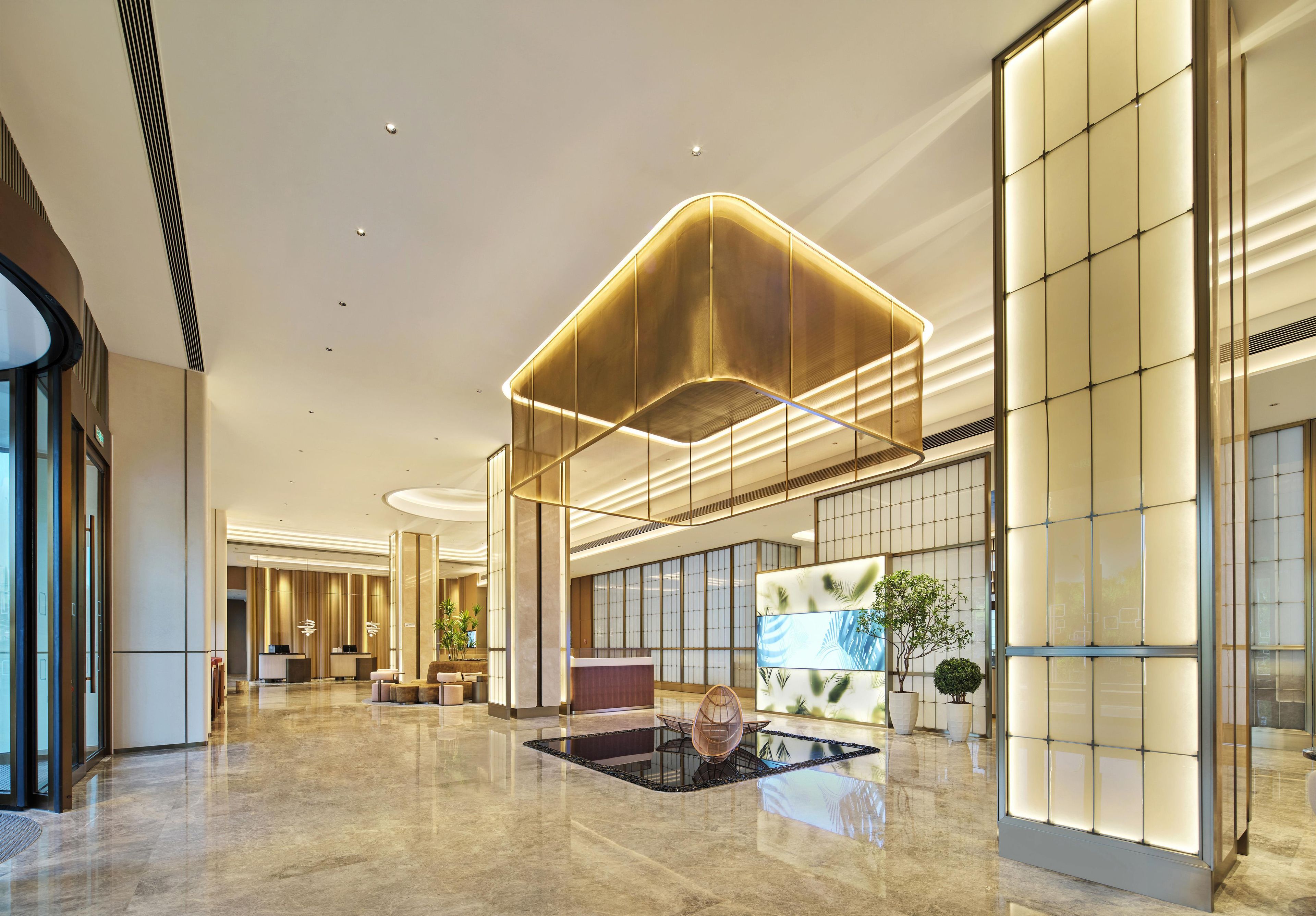 A spacious lobby with a reception desk, seating area, and a large digital display.