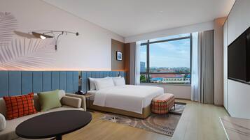 A modern hotel room with a large bed, a sofa, a small table, and a TV.