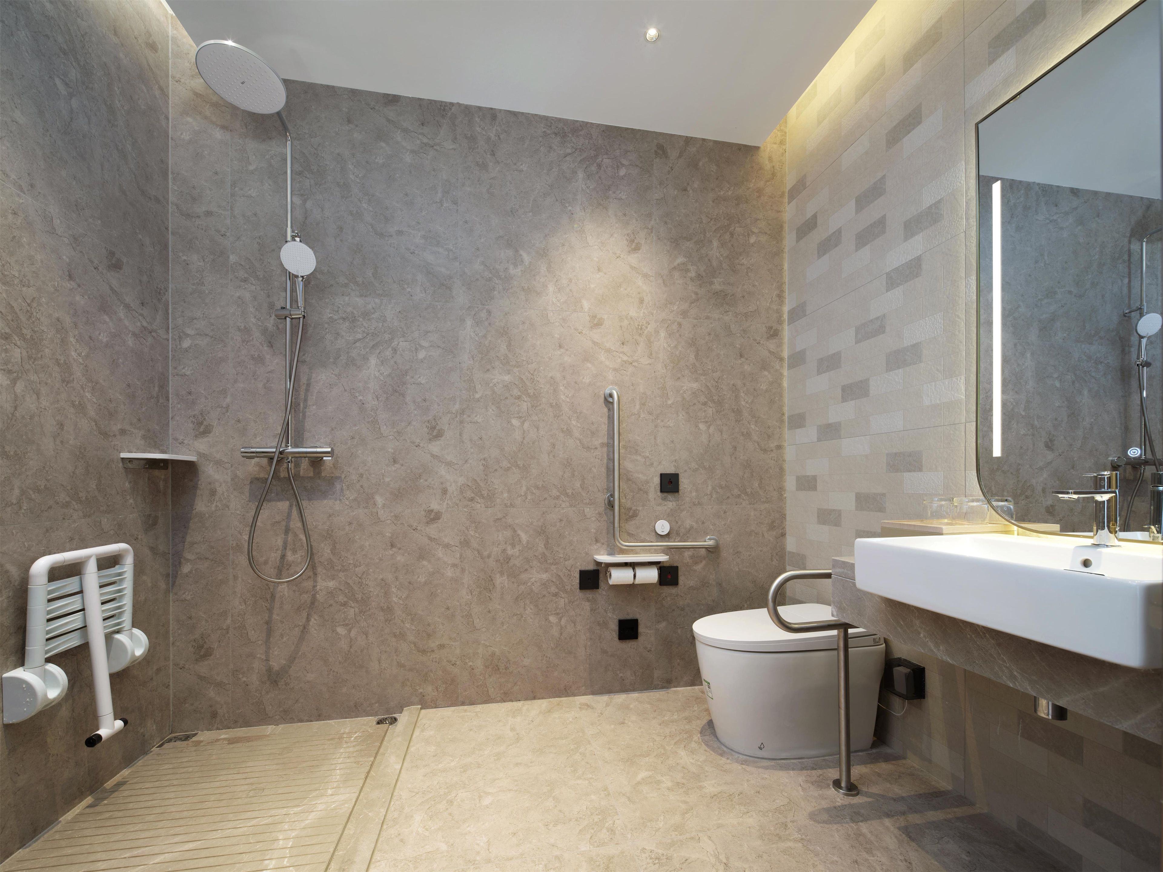 A modern bathroom with a walk-in shower, a toilet with a bidet attachment, and a large mirror above the sink.