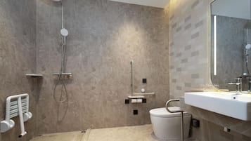 A modern bathroom with a walk-in shower, a toilet with a bidet attachment, and a large mirror above the sink.