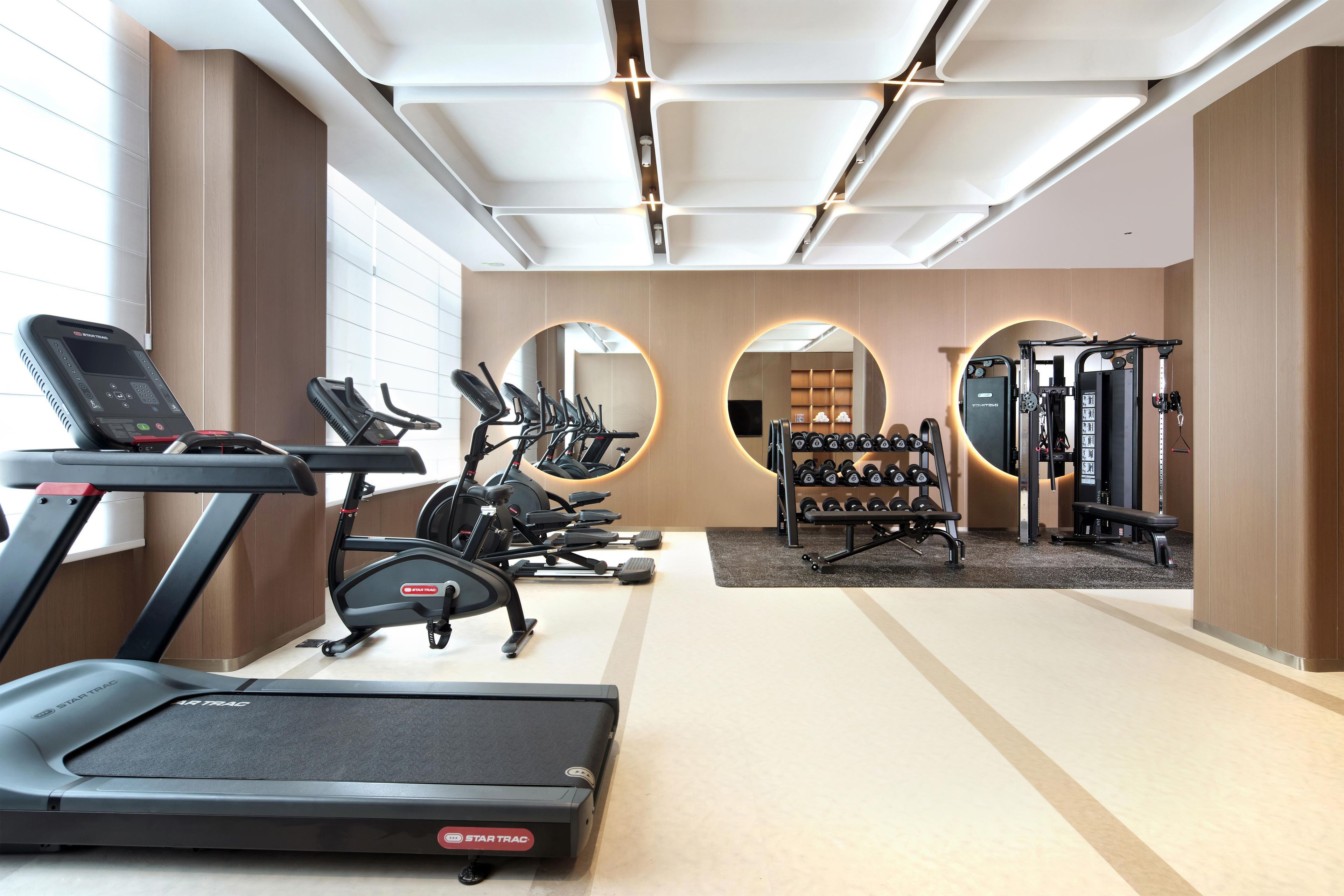A modern gym with treadmills, elliptical machines, and free weights.