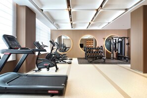 A modern gym with treadmills, elliptical machines, and free weights.
