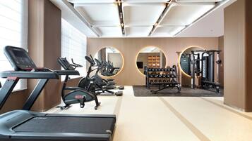 A modern gym with treadmills, elliptical machines, and free weights.