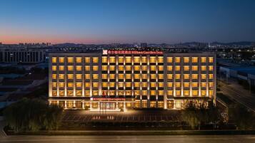 A multi-story hotel with illuminated windows and a clear view of the surrounding cityscape at dusk.