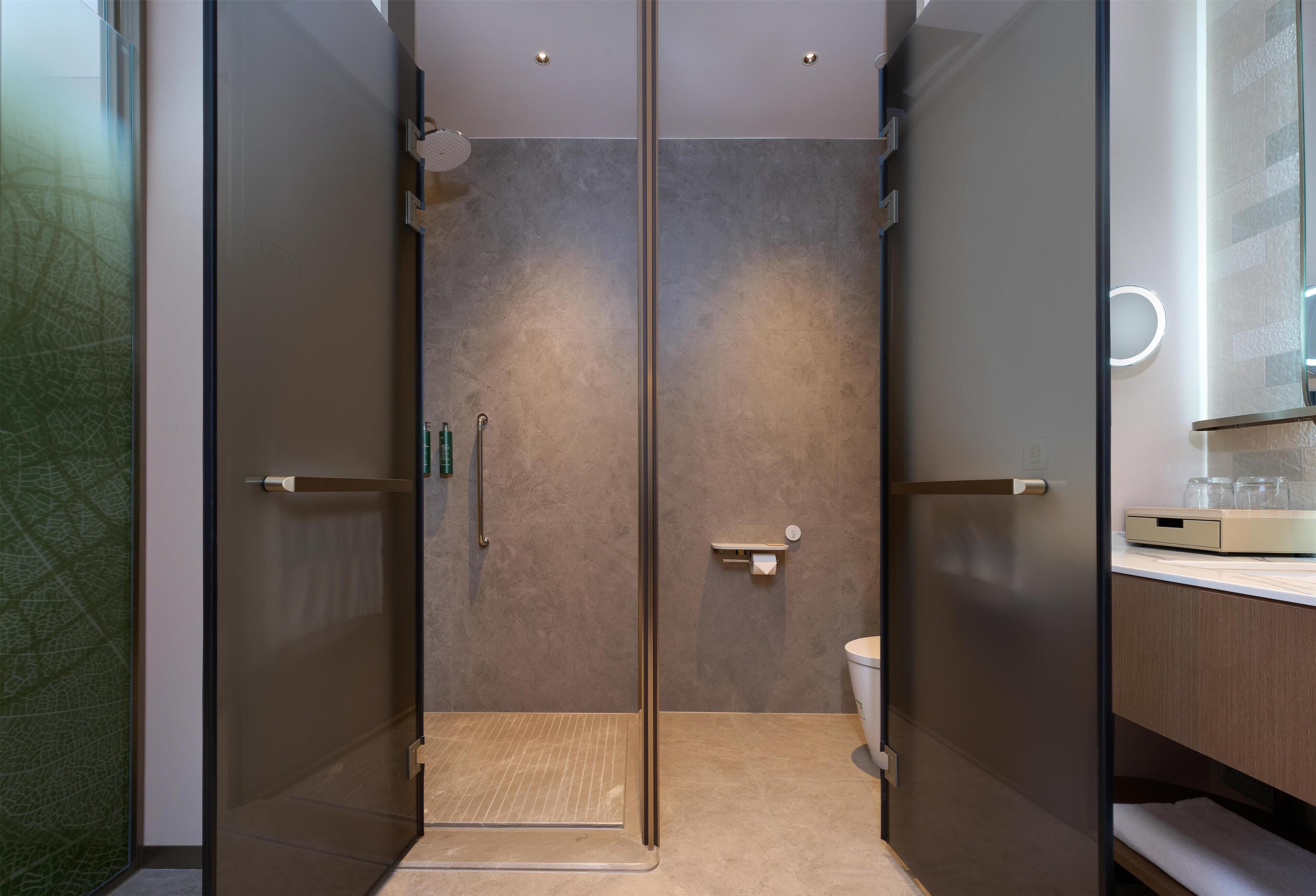 A modern bathroom with a glass shower enclosure, a toilet, and a vanity with a mirror.