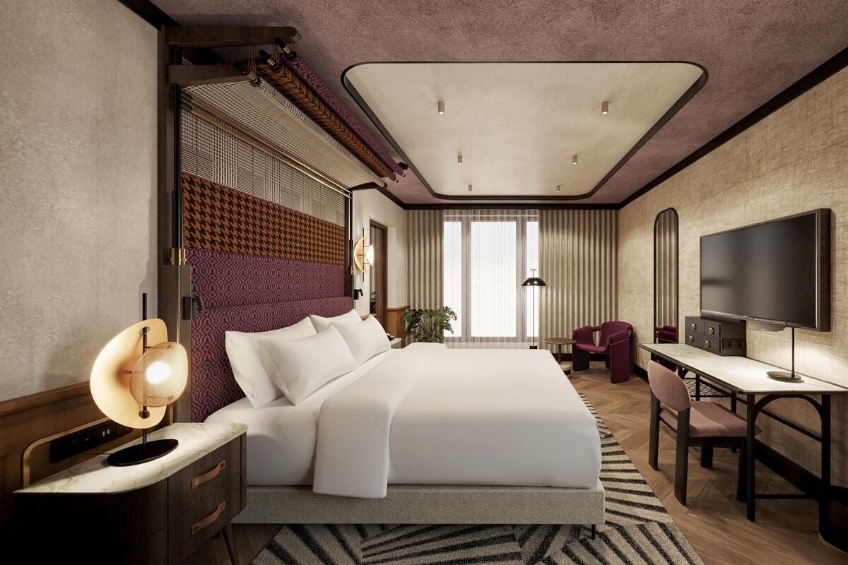 Una habitación de hotel moderna con una cama grande, un escritorio, un televisor de pantalla plana y vistas a la ciudad.