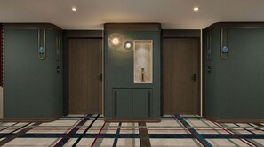 Un pasillo de hotel con tres puertas, una alfombra estampada y un aplique en la pared.