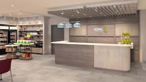 A modern hotel lobby with a reception desk, snack display, and a 'HOME 2' sign. - Home2 Suites By Hilton Barrie (Barrie)