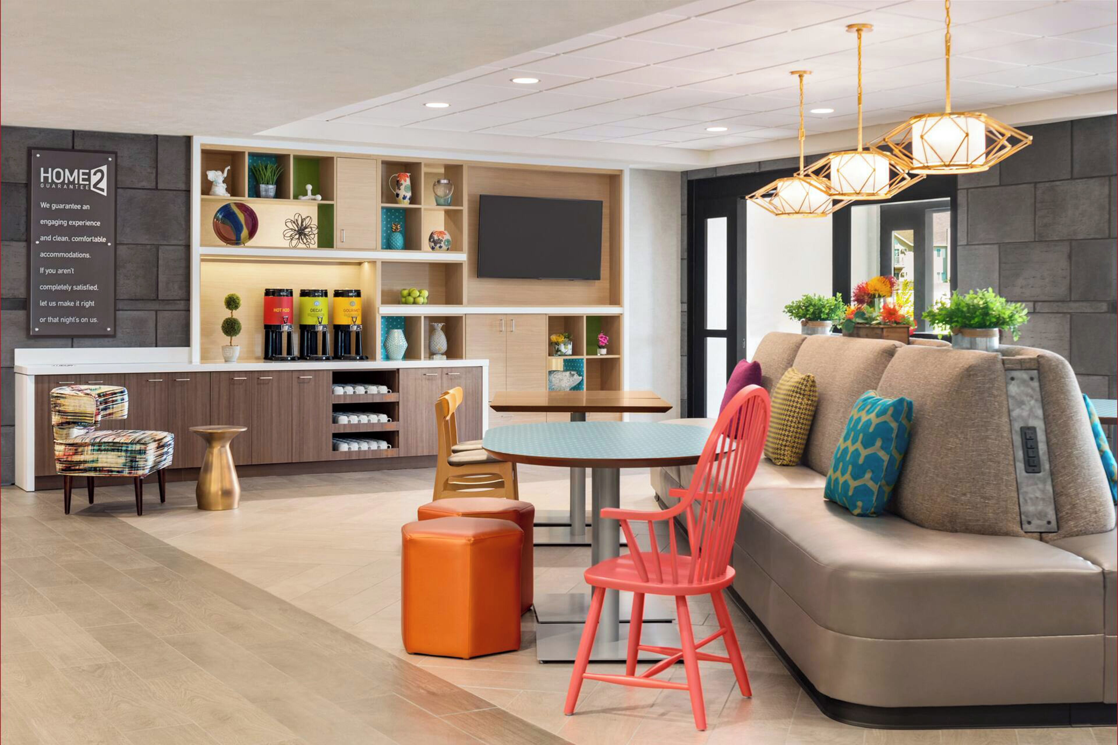 Habitació d'hotel moderna amb sofà, cadires, taula de dinar, zona de cuina i televisió.