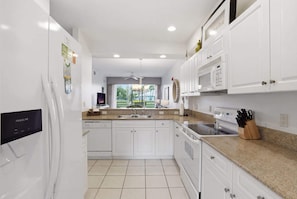 A modern kitchen with white cabinetry, a built-in oven, a microwave, and a stainless steel sink. - 414 - Green Links First Floor -Sleeps 6 (Naples)