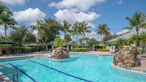A swimming pool with clear blue water, surrounded by palm trees and lounge chairs. - 414 -Wheelchair Accessible - Sleeps 6 (Naples)