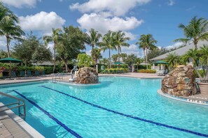 A swimming pool with clear blue water, surrounded by palm trees and lounge chairs. - 414 -Wheelchair Accessible - Sleeps 6 (Naples)