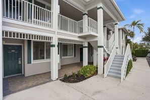 A multi-story building with a covered outdoor area, a staircase, and a door with a number plate. - 414 - Green Links First Floor -Sleeps 6 (Naples)