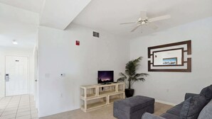 A living room with a television, a ceiling fan, a plant, and a framed picture on the wall. - 414 -Wheelchair Accessible - Sleeps 6 (Naples)