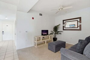 A living room with a television, a ceiling fan, a plant, and a framed picture on the wall. - 414 -Wheelchair Accessible - Sleeps 6 (Naples)