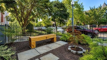 A park with a wooden bench, stone pathways, and a metal fence.
