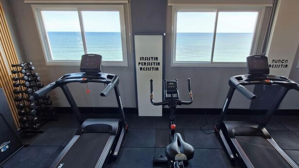 Un gimnasio con dos cintas de correr, una bicicleta estática y una pared con mensajes motivacionales.