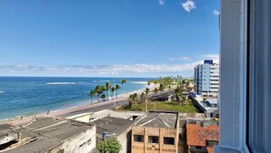A coastal cityscape with a beach, palm trees, and a mix of modern and older buildings. - COPIA0108 - Edifício Essencial Piata (Salvador)