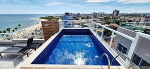A rooftop pool with a view of the beach and cityscape. - COPIA0108 - Edifício Essencial Piata (Salvador)