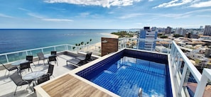 A rooftop pool with a view of the ocean and cityscape. - COPIA0108 - Edifício Essencial Piata (Salvador)
