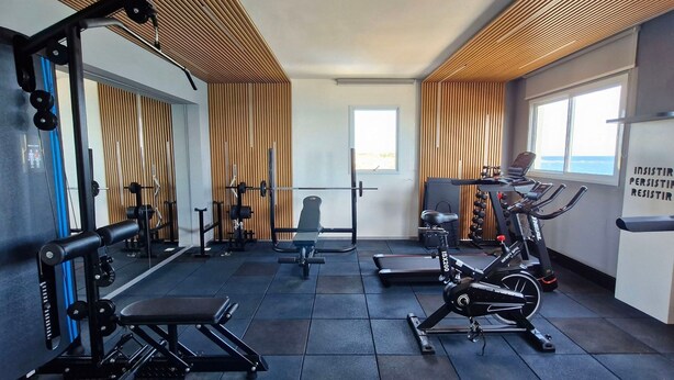 A gym with exercise equipment, a bench, and a wall with motivational text. - COPIA0108 - Edifício Essencial Piata (Salvador)