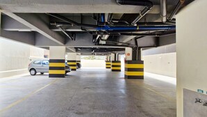 A parking garage with striped bollards and a car parked in the distance. - COPIA0108 - Edifício Essencial Piata (Salvador)