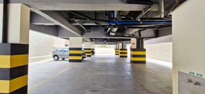 A parking garage with striped bollards and a car parked in the distance. - COPIA0108 - Edifício Essencial Piata (Salvador)