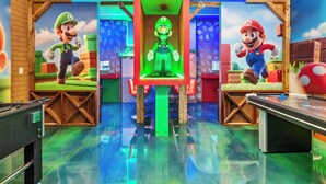 Ein Raum mit zwei Gaming-Stationen im Mario-Design, jeweils mit Bildschirm und Stuhl.