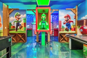 A room with two Mario-themed gaming stations, each with a screen and a chair. - Luxury 8BR Themed Villa With Private Pool (Clermont)