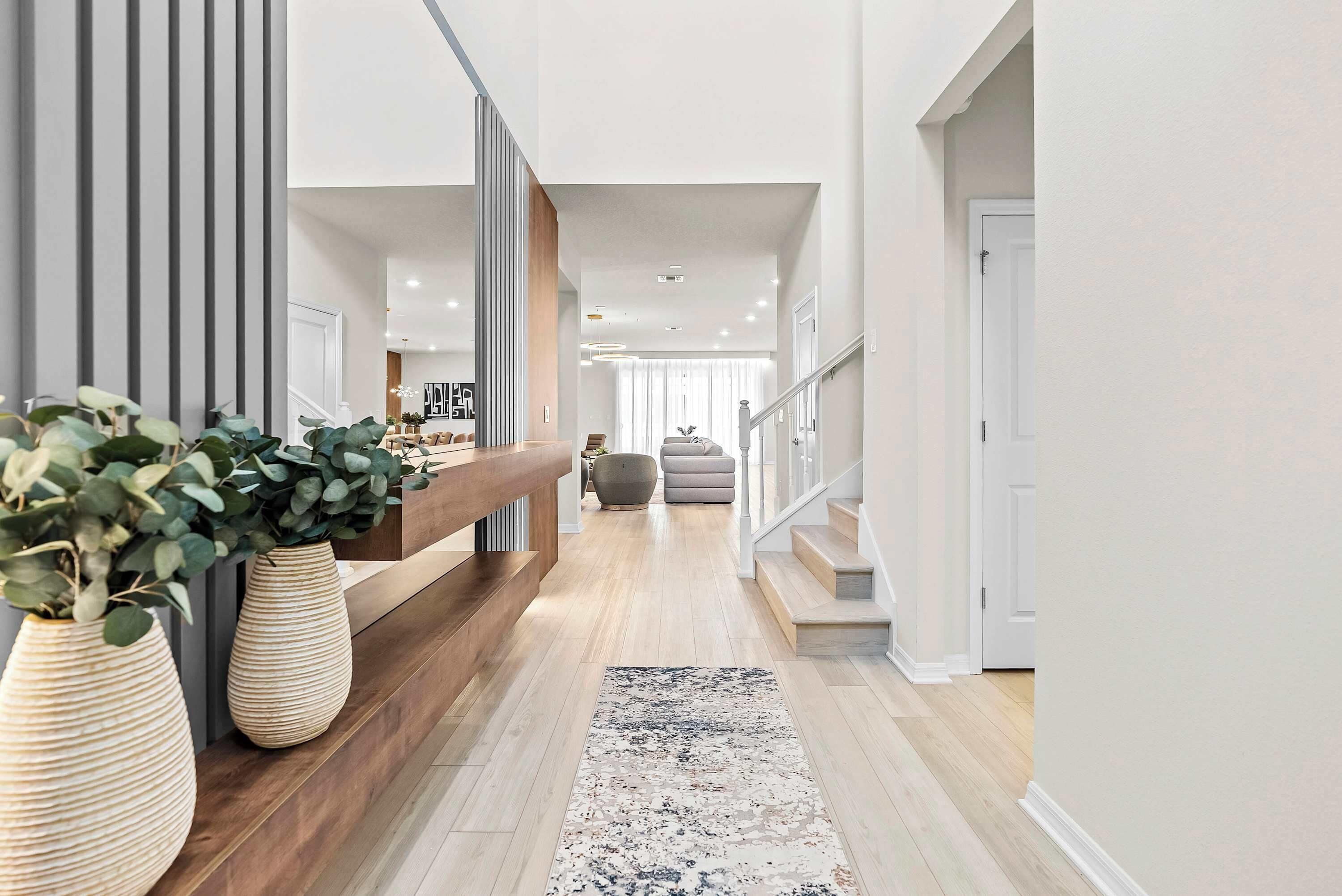 A modern interior with a wooden bench, a large potted plant, and a staircase leading to another level.