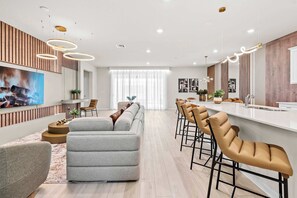 A modern kitchen with a central island, bar stools, and pendant lighting. - Luxury 8BR Themed Villa With Private Pool (Clermont)