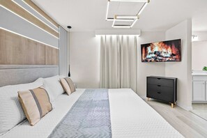 A modern bedroom with a large bed, a flat-screen TV, and a minimalist dresser. - Luxury 8BR Themed Villa With Private Pool (Clermont)