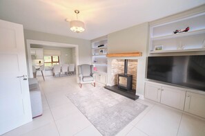 A spacious living room with a fireplace, a TV, and a dining area with chairs.