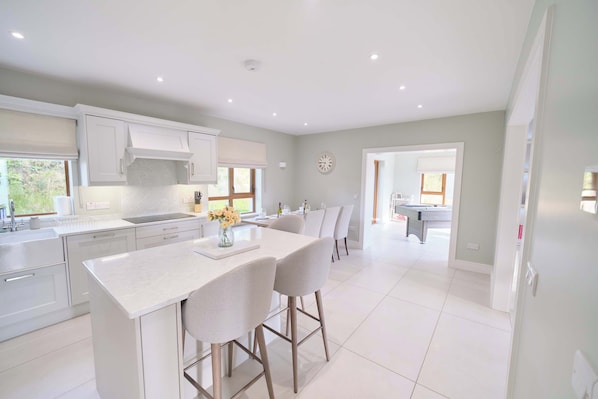 A modern kitchen with white cabinetry, a central island, and a dining area with two chairs.