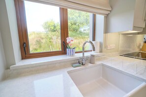 A kitchen with a large window, a sink, and a dish rack.
