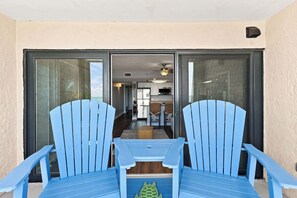A view of a sliding glass door leading into a room with a kitchen area, two blue chairs, and a small table. - Serenity at Sea Pointe Oceanfront Condo with Pool (North Myrtle Beach)