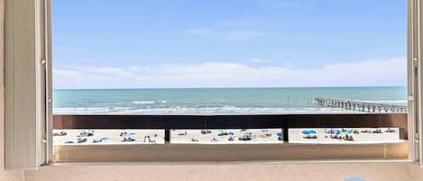 A balcony with a view of a beach and pier.