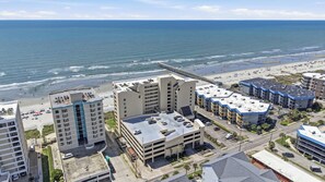 A coastal hotel with multiple buildings, a parking lot, and a beach view. - Serenity at Sea Pointe Oceanfront Condo with Pool (North Myrtle Beach)