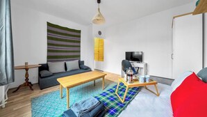 Ein modernes Wohnzimmer mit einer Couch, einem Holztisch, einem Fernseher und einem gemusterten Teppich.